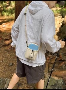 Detail of outdoor mini crossbody bag with drawstring pocket in off-white and blue