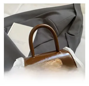 Close-up of brown leather bag with plush bear patch and delicate white lace trim detail