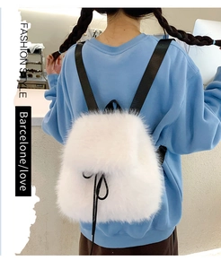 Detail of white fluffy plush backpack with drawstring closure and black bow accent