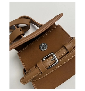 Macro shot of brown leather mini bag with silver buckle and magnetic closure detail