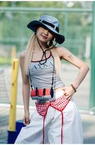 Outdoor crossbody bag in orange and blue shown with sporty apparel on a tennis court