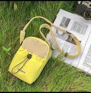 Detail of yellow nylon crossbody bag with drawstring pocket on green grass outdoor