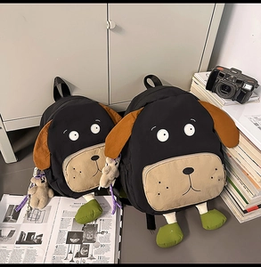 Detail of cartoon rottweiler dog backpack with plush ears and a cute bear charm