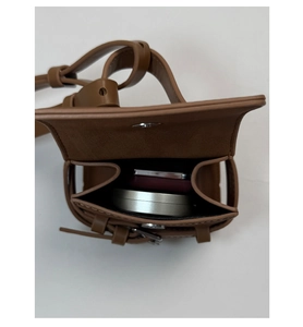 Detailed interior of a brown leather mini flap bag showing storage for makeup items