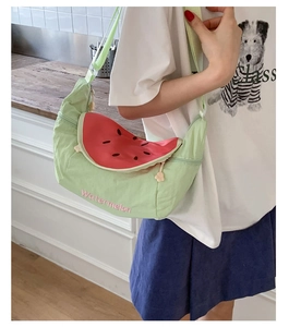Detail of watermelon shaped crossbody bag with green fabric and red seed pattern