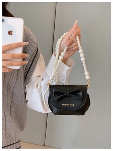 Detail view of mini black girls purse with large bow, pearl handle and fashion bag text
