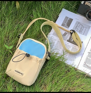 Detail of a beige and blue nylon crossbody phone bag with drawstring and buckle