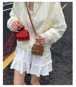 Miniature square crossbody bags in red and brown leather shown on a street backdrop