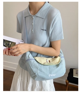 Detail of light blue crossbody bag with pear-shaped flap and white letter embroidery