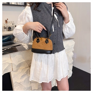 Quilted mini shell bag in brown and black leather worn by a model in a minimalist setting