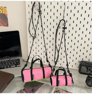 Detail view of pink cylinder sports bags in two sizes with adjustable straps on a pegboard