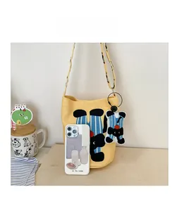 Yellow canvas tote bag with cartoon cat print shown beside a phone for size comparison