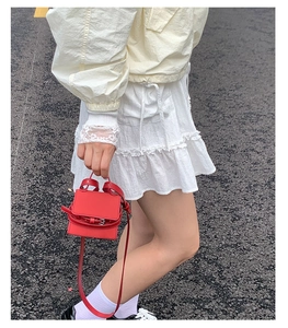 Chic red mini square bag worn as a crossbody and handbag by a model on a street