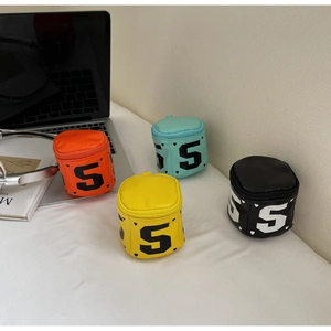 Mini cylindrical coin purses in four colors with heart patterns on a lifestyle desk setup