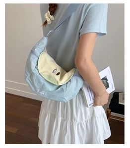 Detail of light blue nylon crossbody bag with yellow flap and pear embroidery detail