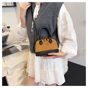 Détail d'un sac à main en daim matelassé marron avec garniture en cuir noir et zip