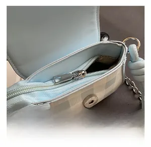 Macro detail of plaid kid bag featuring silver zipper and magnetic snap closure