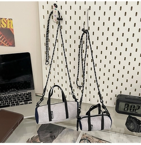 Grey mini cylinder crossbody bags hanging on a white pegboard for outdoor sports travel