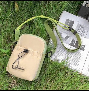 Close-up of contrast color crossbody bag with drawstring pocket on green grass