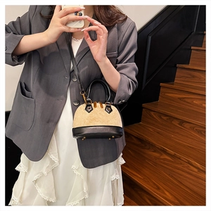 Detail of beige quilted shell bag with black contrast handles and gold hardware
