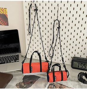 Close-up of orange mini running bags with knit texture on a white pegboard setup