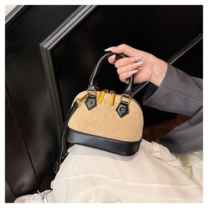 Detail of shell-shaped handbag with khaki quilted texture and black leather stitching