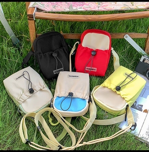 Outdoor display of crossbody bags in five colors with drawstring front pocket and adjustable straps
