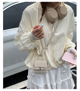 Micro cream crossbody bag detail with buckle decor on model wearing a lace skirt