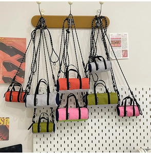 Detail of colorful mini cylinder crossbody bags with adjustable braided rope straps on display