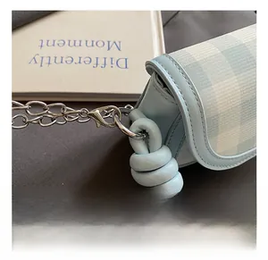 Detail of blue plaid fabric and leather knot with silver chain hook on mini bag