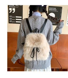 Detail view of plush beige faux fur mini backpack with black drawstring bow and nylon straps