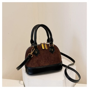 Close-up of brown quilted faux suede shell bag with black leather accents and gold hardware