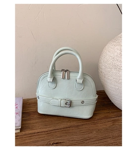 Detail of mint green shell handbag featuring textured pebble leather and silver buckle