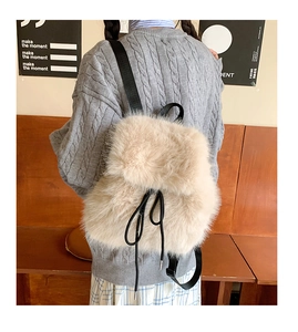 Detail of plush cream faux fur backpack featuring black drawstring and adjustable straps