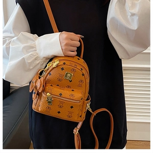 Dettaglio di mini zaino marrone vintage con motivo orso e placca logo in metallo dorato