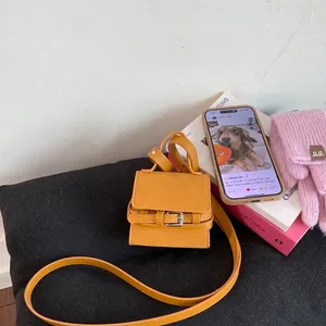 Detailed view of a yellow mini flap bag with metal buckle on a textured cushion