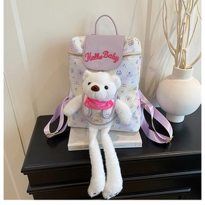 Detail of cute cream backpack with Hello Baby embroidery, teddy bear, and purple flap