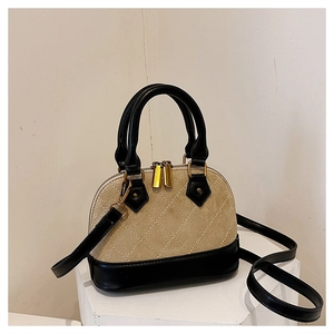Detail of diamond-quilted beige suede and black leather on a mini shell-shaped handbag