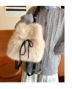 Close-up of beige faux fur backpack texture with black drawstrings on a grey knit sweater