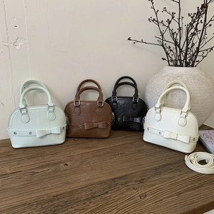 Detail of mini shell bags in four colors featuring bow design and premium texture
