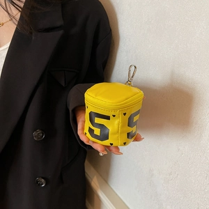 Mini yellow round coin purse with heart patterns and metallic clasp held by model