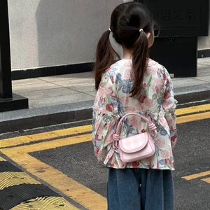 Toddler model wearing a pink plaid crossbody bag with metal chain strap and knot handle