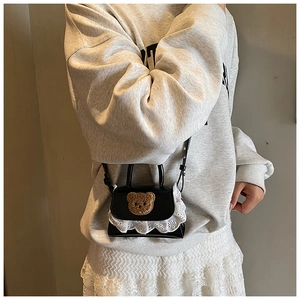 Detail of mini black bear purse with lace trim and plush patch on a crossbody bag