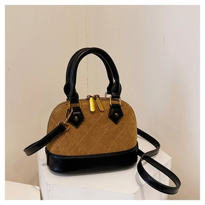 Close-up of quilted shell bag with brown suede and black leather stitching detail