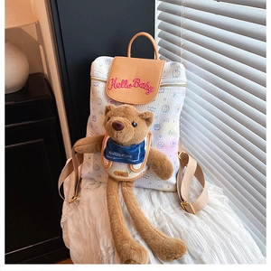 Close-up of white graffiti backpack with leather flap and cute long-legged plush bear