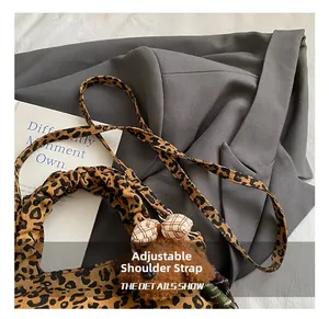 Detail of leopard print crossbody bag with plush bear charm and adjustable strap