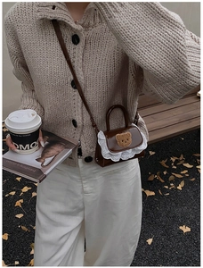 Close-up of brown faux leather mini bag featuring white lace trim and teddy bear applique
