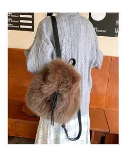 Close-up of brown faux fur backpack texture and black strap detail on model