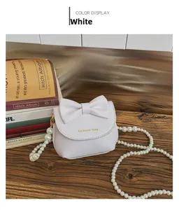 Close-up of white mini purse with pearl chain and bow detail on wooden background