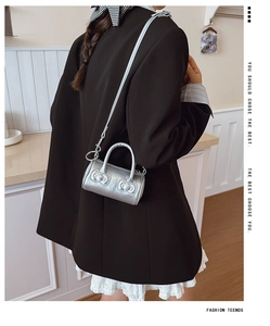 Detail of silver metallic mini bucket bag with bow accents worn by a model